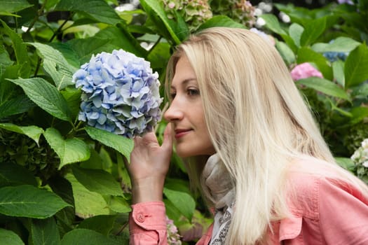 Portrait of a blonde woman smelling hydrangea flowers