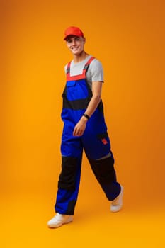 Full length shot of a young male worker in uniform on yellow background in studio