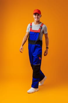 Full length shot of a young male worker in uniform on yellow background in studio