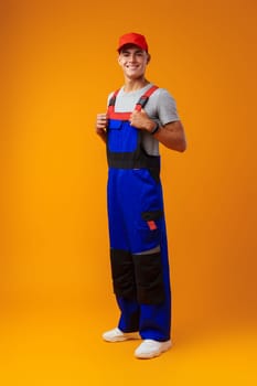 Full length shot of a young male worker in uniform on yellow background in studio