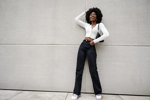 woman posing in front of a gray concrete wall in the city