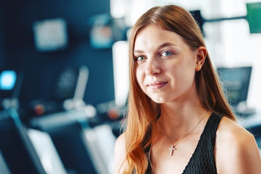 Smiling teen girl training in a fitness club, close up