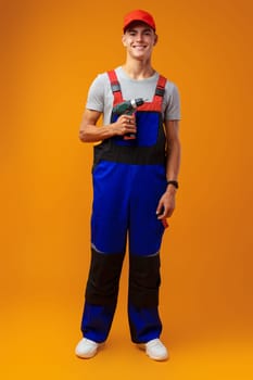 Handsome young handyman holding screwdriver against yellow background, close up