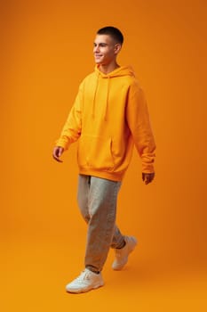 Full length portrait of young man standing on yellow background in studio