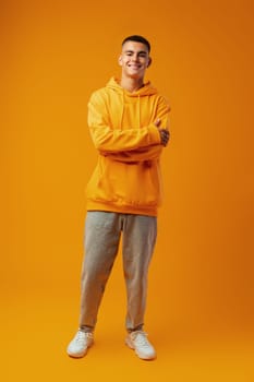 Full length portrait of young man standing on yellow background in studio