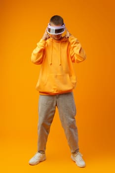 Young urban style man in sweatshirt and visor on yellow studio background, close up