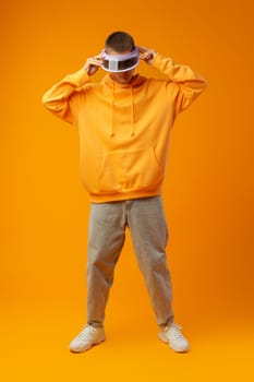 Young urban style man in sweatshirt and visor on yellow studio background, close up