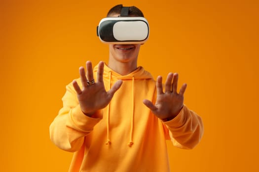 Young man using virtual reality headset against yellow background in studio