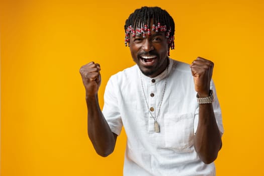 Young african man standing over yellow background doing winner gesture, close up