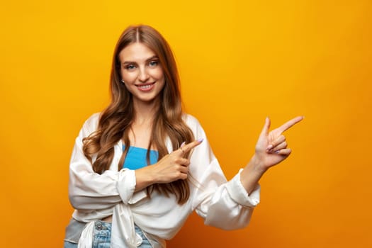 Young pretty woman pointing at copy space in photo studio