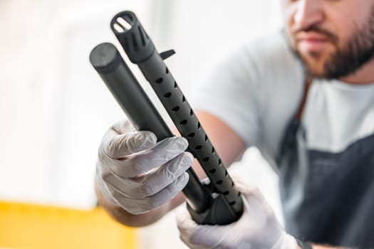 The gunsmith maintaining his shotgun rifle in a workshop