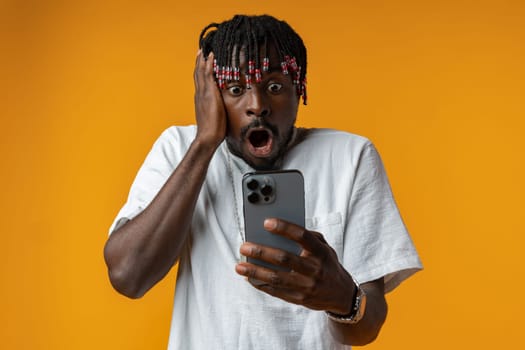 Young african man using smartphone over isolated yellow background close up