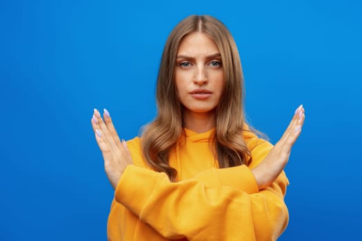 Portrait of attractive girl showing reject sign with crossed arms in studio, close up