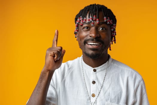 Young african man over isolated yellow background pointing upwards having an idea