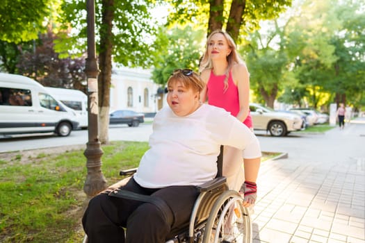 Young female caregiver pushing wheelchair with mature female person with disability across city street