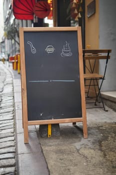 Empty wooden blackboard mockup standing outdoors in front of cafe .