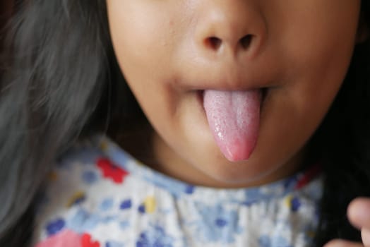 child shows his tongue closeup .