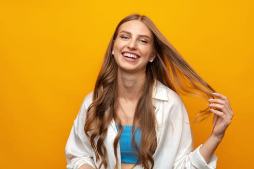 Charming blonde woman stands on yellow background looks directly at camera, close up