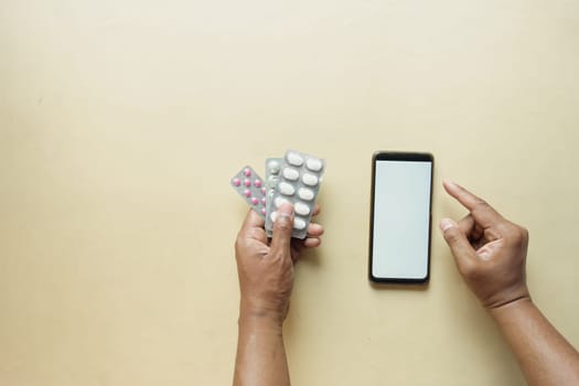 young man hand holding medicine pill and smart phone on a table .