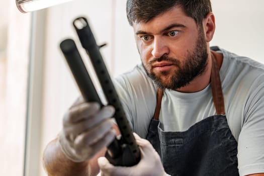 The gunsmith maintaining his shotgun rifle in a workshop