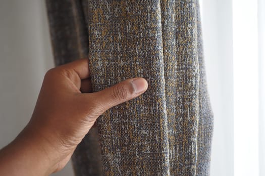 close up of holding a gray fabric curtain.,