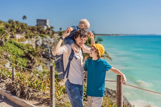 Father and two sons tourists enjoying the view Pre-Columbian Mayan walled city of Tulum, Quintana Roo, Mexico, North America, Tulum, Mexico. El Castillo - castle the Mayan city of Tulum main temple.