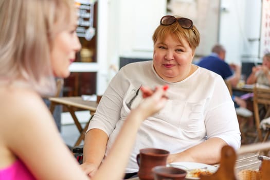 Portrait of two women, a mother and her daughter sitting in a outdoor cafe