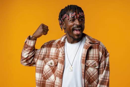 Young african man standing over yellow background doing winner gesture, close up