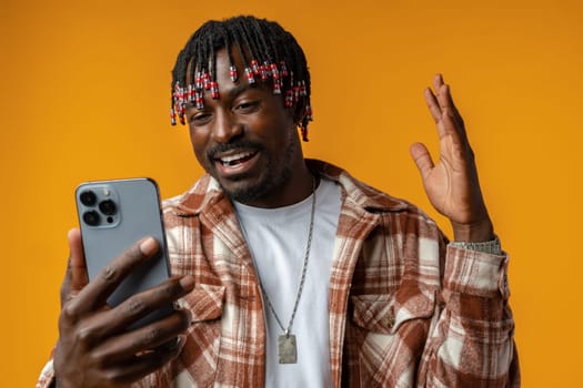 Young african man using smartphone over isolated yellow background close up