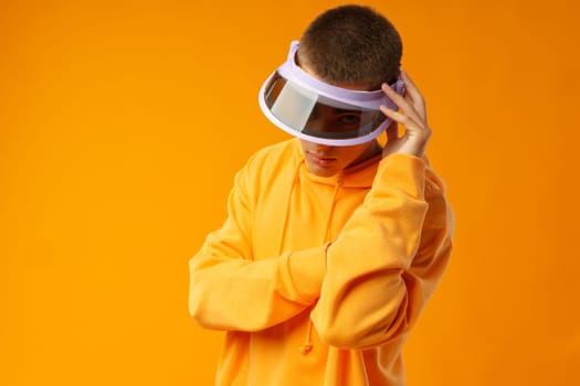 Young urban style man in sweatshirt and visor on yellow studio background, close up