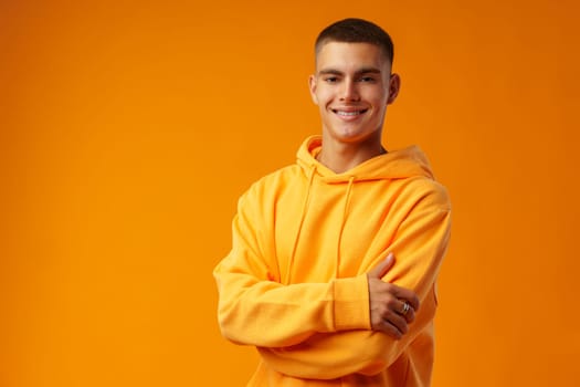 Happy smiling young man looking to camera over yellow background, close up