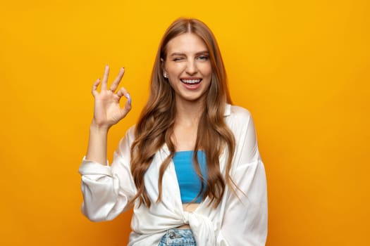 Young caucasian woman isolated on yellow background showing ok sign with fingers