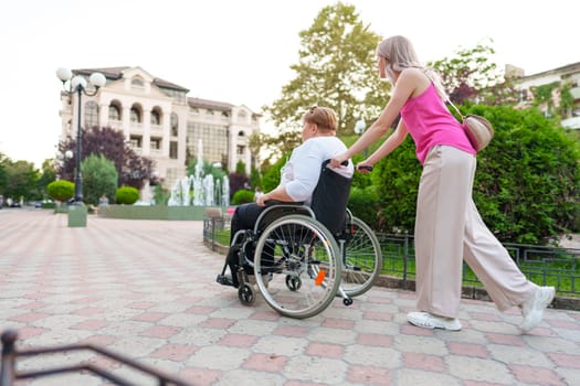 Young woman helping mature woman in wheelchair in the city street