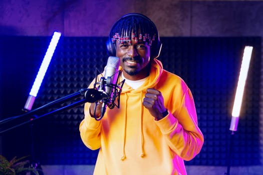 Young African performer recording his new track in recording studio, close up portrait