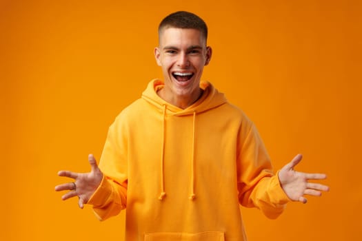 Portrait of a happy young man celebrating success against yellow background in studio