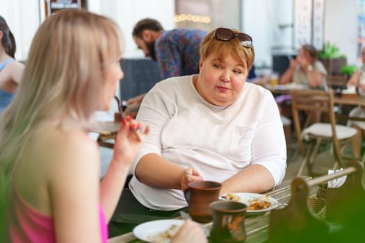 Portrait of two women, a mother and her daughter sitting in a outdoor cafe