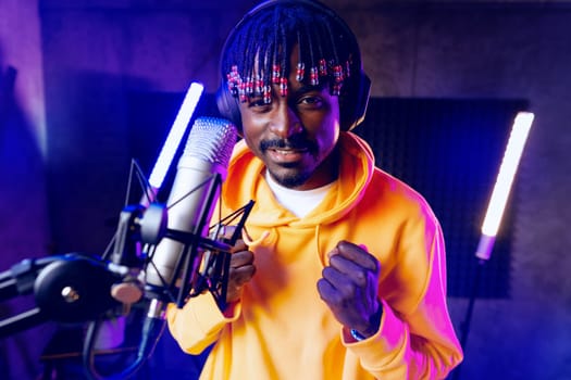 Young African performer recording his new track in recording studio, close up portrait