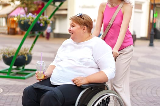 Young woman helping mature woman in wheelchair in the city street