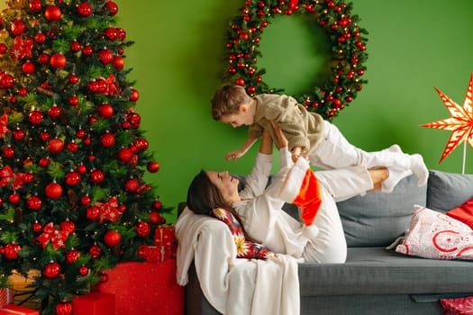 Mother sitting on a sofa with her son in living room decorated for Christmas, close up