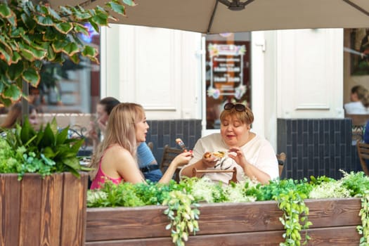 Portrait of two women, a mother and her daughter sitting in a outdoor cafe