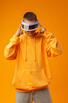 Young urban style man in sweatshirt and visor on yellow studio background, close up