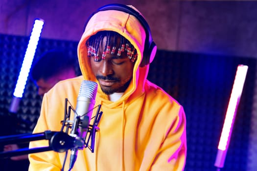 Young African performer recording his new track in recording studio, close up portrait