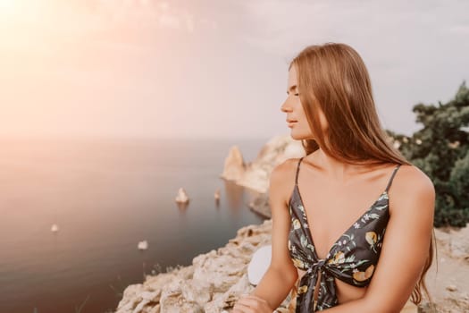 Woman travel sea. Happy tourist taking picture outdoors for memories. Woman traveler looks at the edge of the cliff on the sea bay of mountains, sharing travel adventure journey.