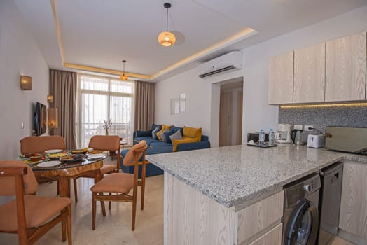 Living room lounge area in luxury apartment show home showing interior design decor furnishing with balcony terrace and open plan kitchen