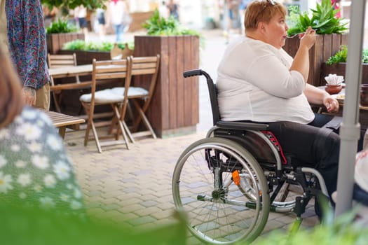 Woman in wheelchair sitting at outdoor cafe table back view