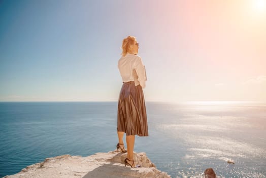 Business woman on nature in white shirt and black skirt. She works with an iPad in the open air with a beautiful view of the sea. The concept of remote work