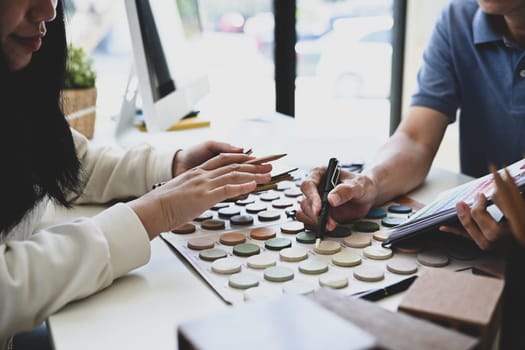 Cropped shot of male designer expert showing color palette to female client in office.