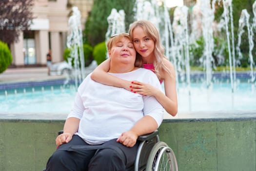 Young daughter taking care of her mother with disability sitting in wheelchair, portrait