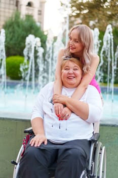 Young daughter taking care of her mother with disability sitting in wheelchair, portrait