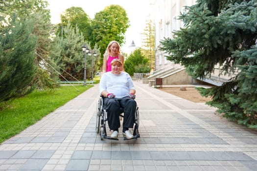 Young female caregiver pushing wheelchair with mature female person with disability across city street